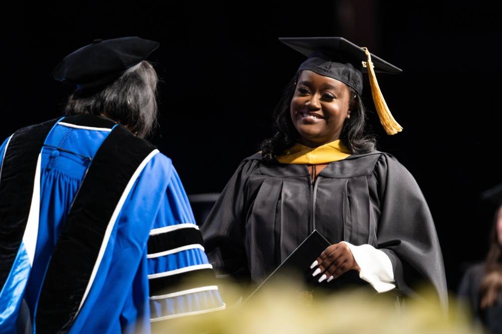 A student at Commencement smiling at President Mantella